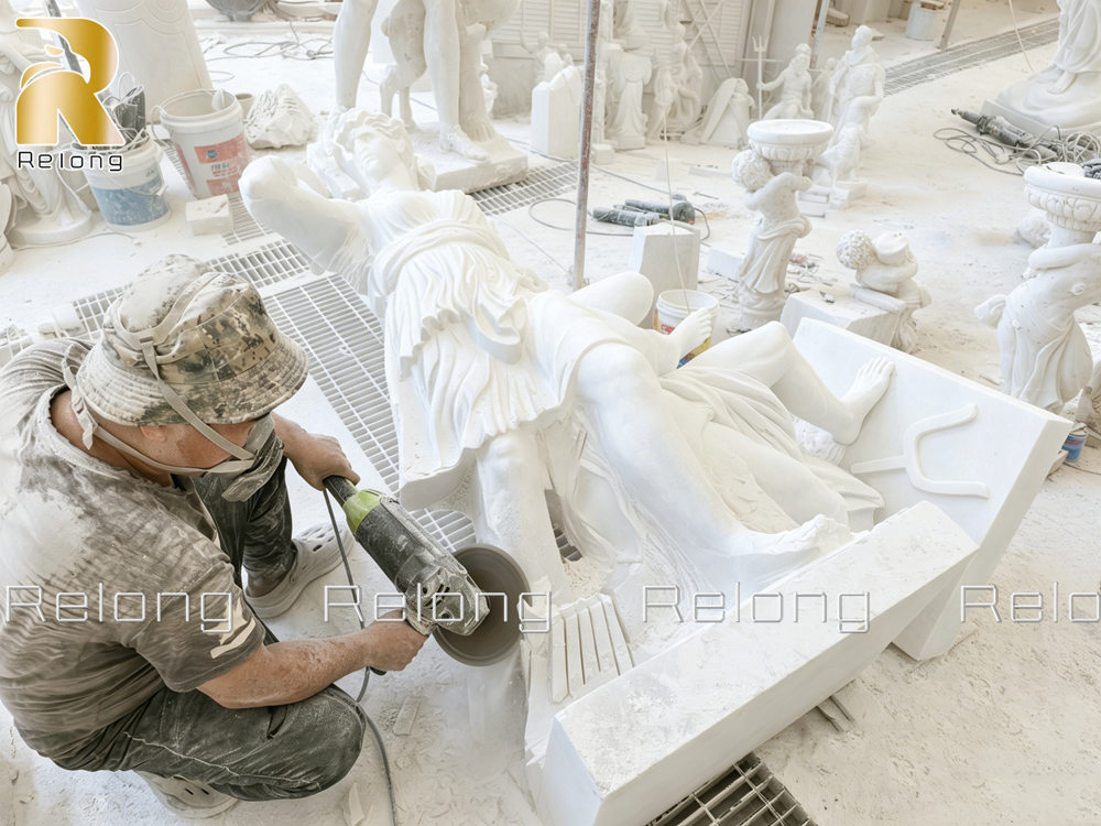 The sculptor is working on the sculpture with tools